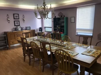 A traditional dining room with a large table, chairs, chandelier, and wooden furniture.